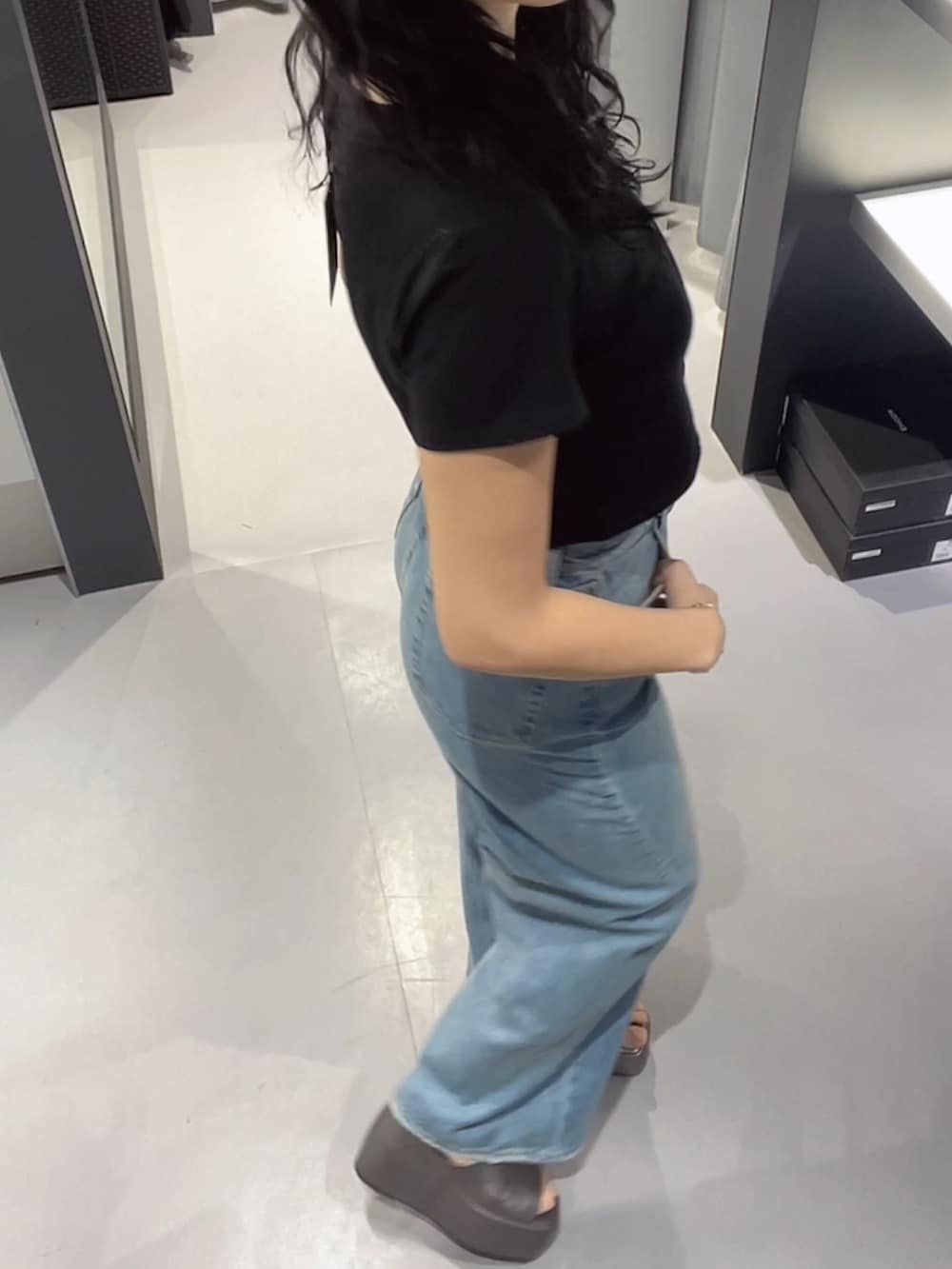 ブラック系のTシャツ/カットソー、ブルー系のデニムパンツ、シルバー系のサンダルを着用したレディースの春コーディネートの2枚目の写真