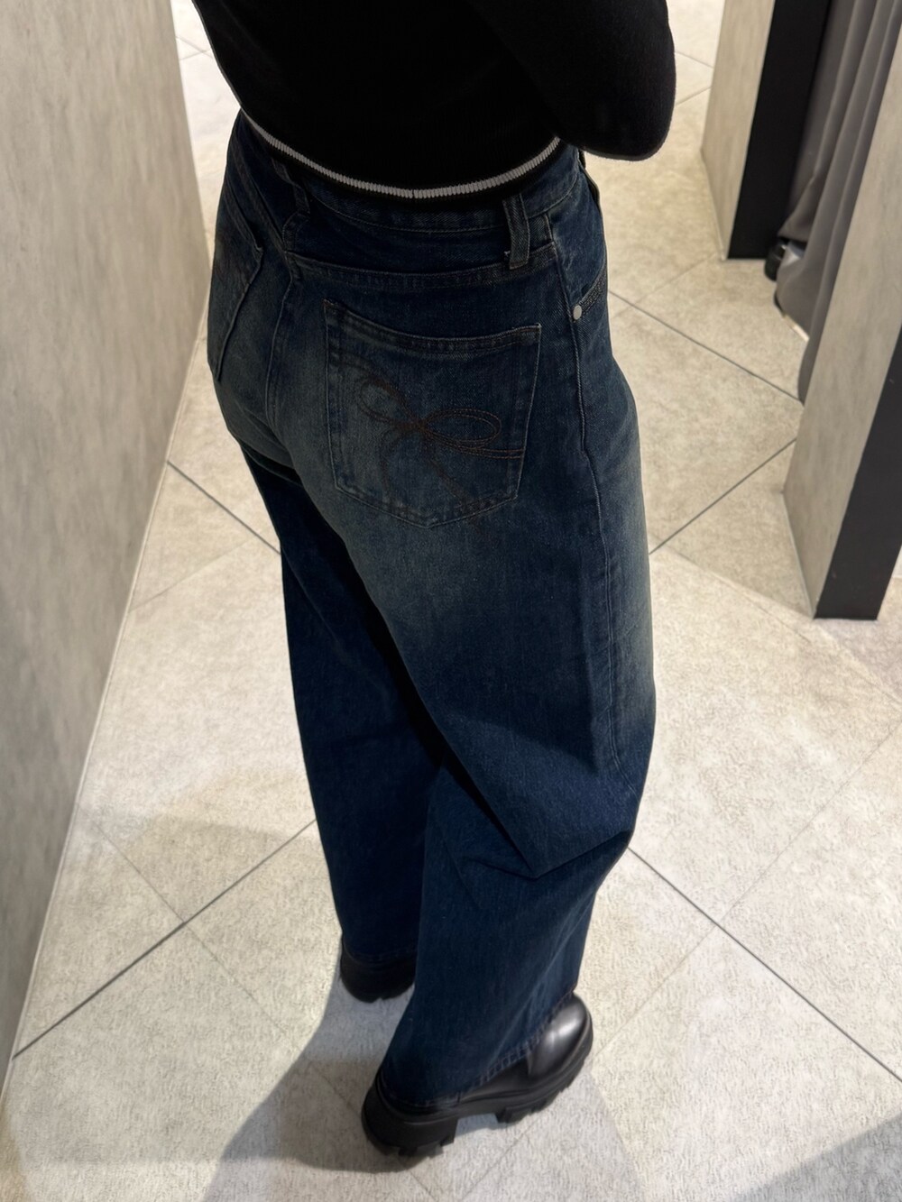 ブラック系のブーツ、ブラック系のニット/セーター、ブルー系のデニムパンツを着用したレディースの秋コーディネートの7枚目の写真