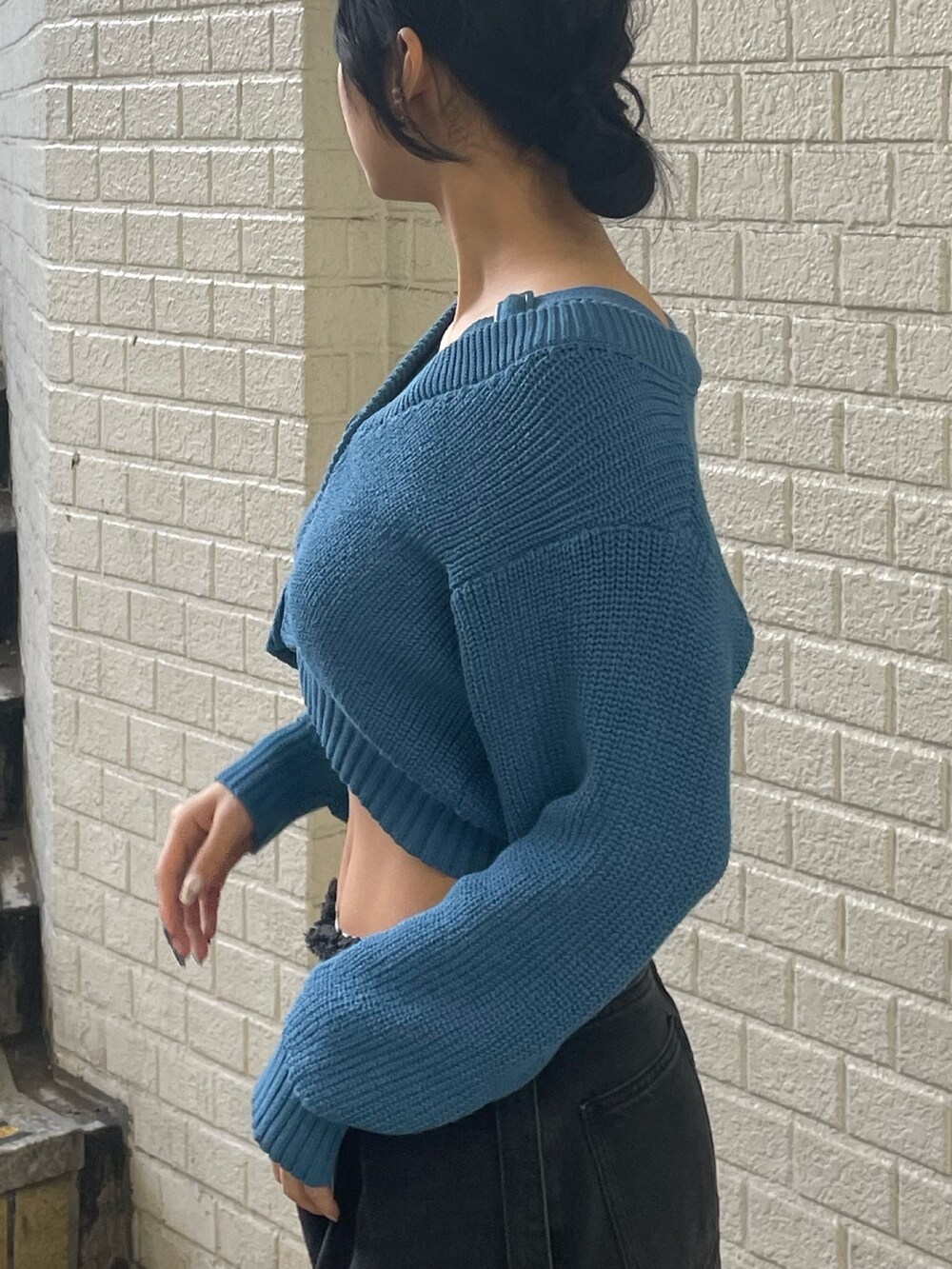 ブルー系のニット/セーター、ブラック系のデニムパンツ、ブラック系のブーツを着用したレディースの春コーディネートの5枚目の写真