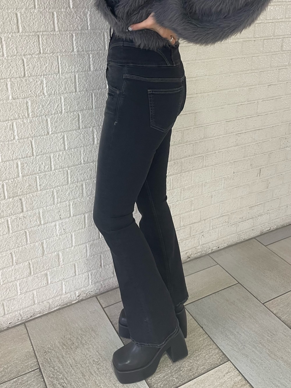 グレー系のニット/セーター、ブラック系のデニムパンツ、ブラック系のブーツを着用したレディースの冬コーディネートの9枚目の写真