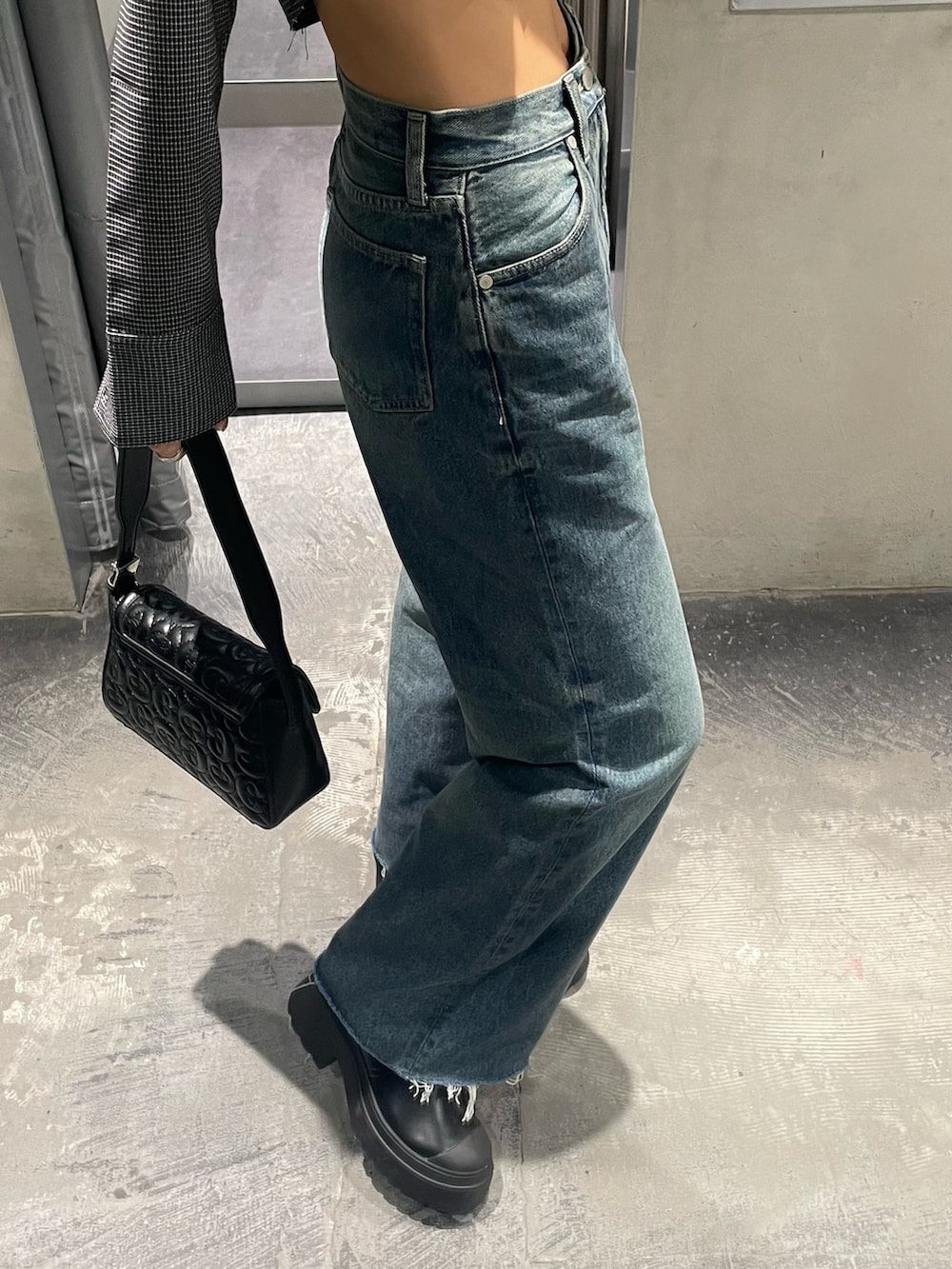 ブルー系のデニムパンツ、ブラック系のブーツ、ブラック系のハンドバッグを着用したレディースの秋コーディネートの4枚目の写真