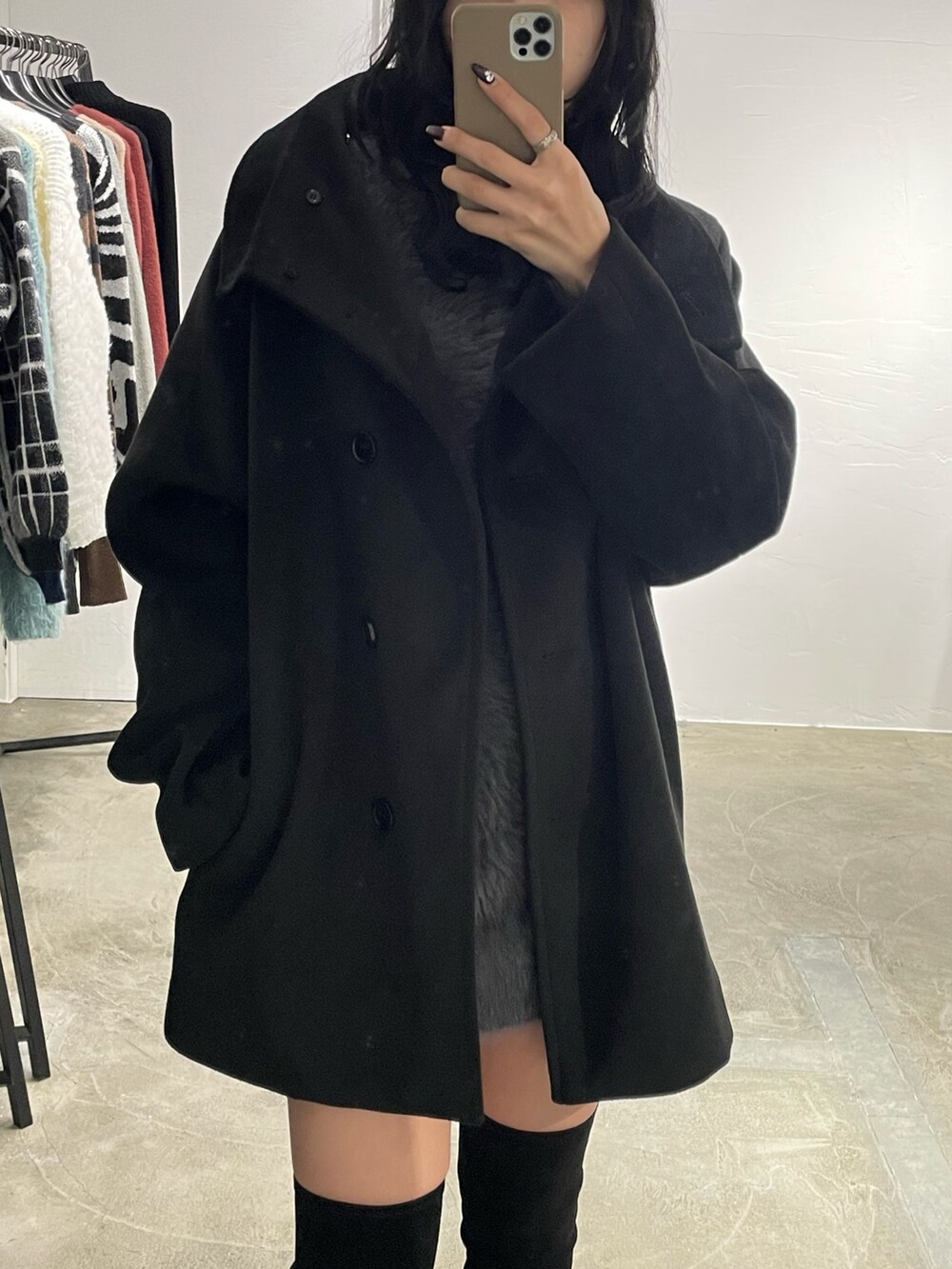 ブラック系のピーコート、グレー系のワンピース、ブラック系のブーツを着用したレディースの冬コーディネートの3枚目の写真