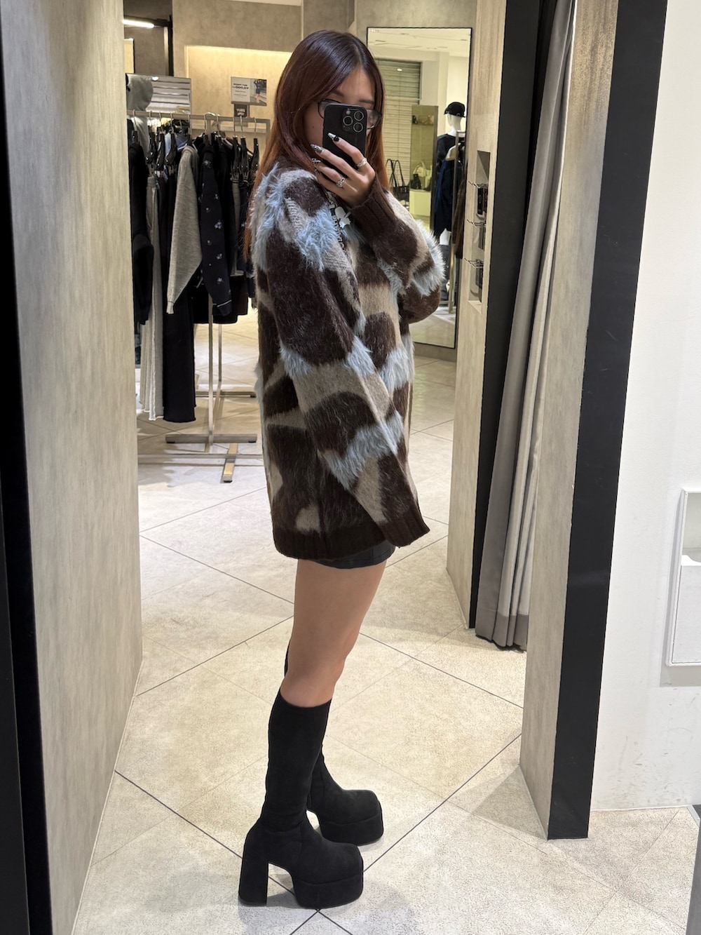 ブラウン系のニット/セーター、ブラック系のスカート、ブラック系のブーツを着用したレディースの秋コーディネートの2枚目の写真