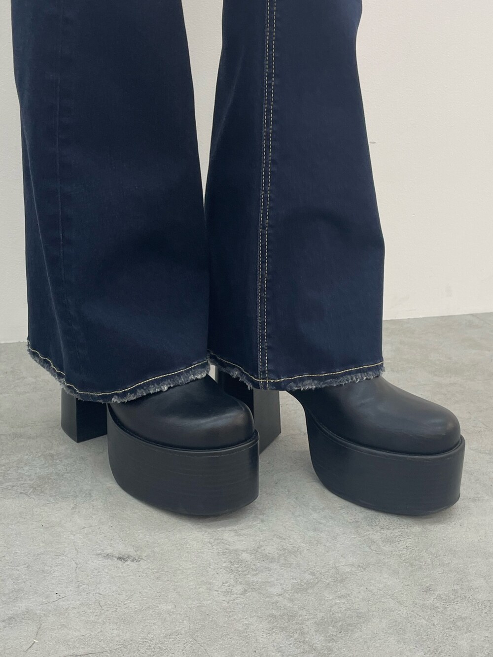 ホワイト系のニット/セーター、ブラック系のデニムパンツ、ブラック系のブーツを着用したレディースの秋コーディネートの9枚目の写真