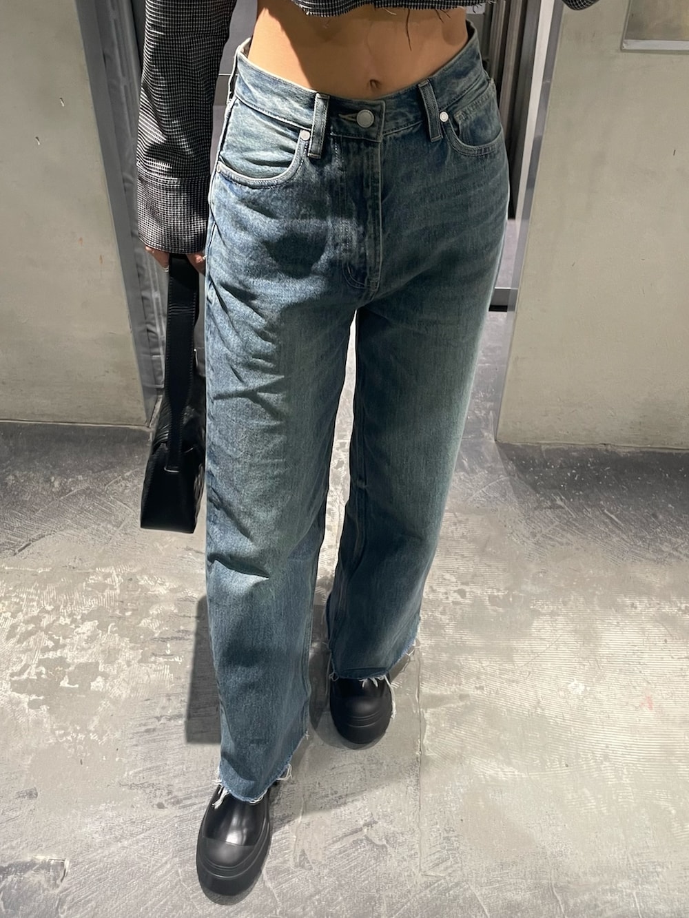 ブルー系のデニムパンツ、ブラック系のブーツ、ブラック系のハンドバッグを着用したレディースの秋コーディネートの3枚目の写真