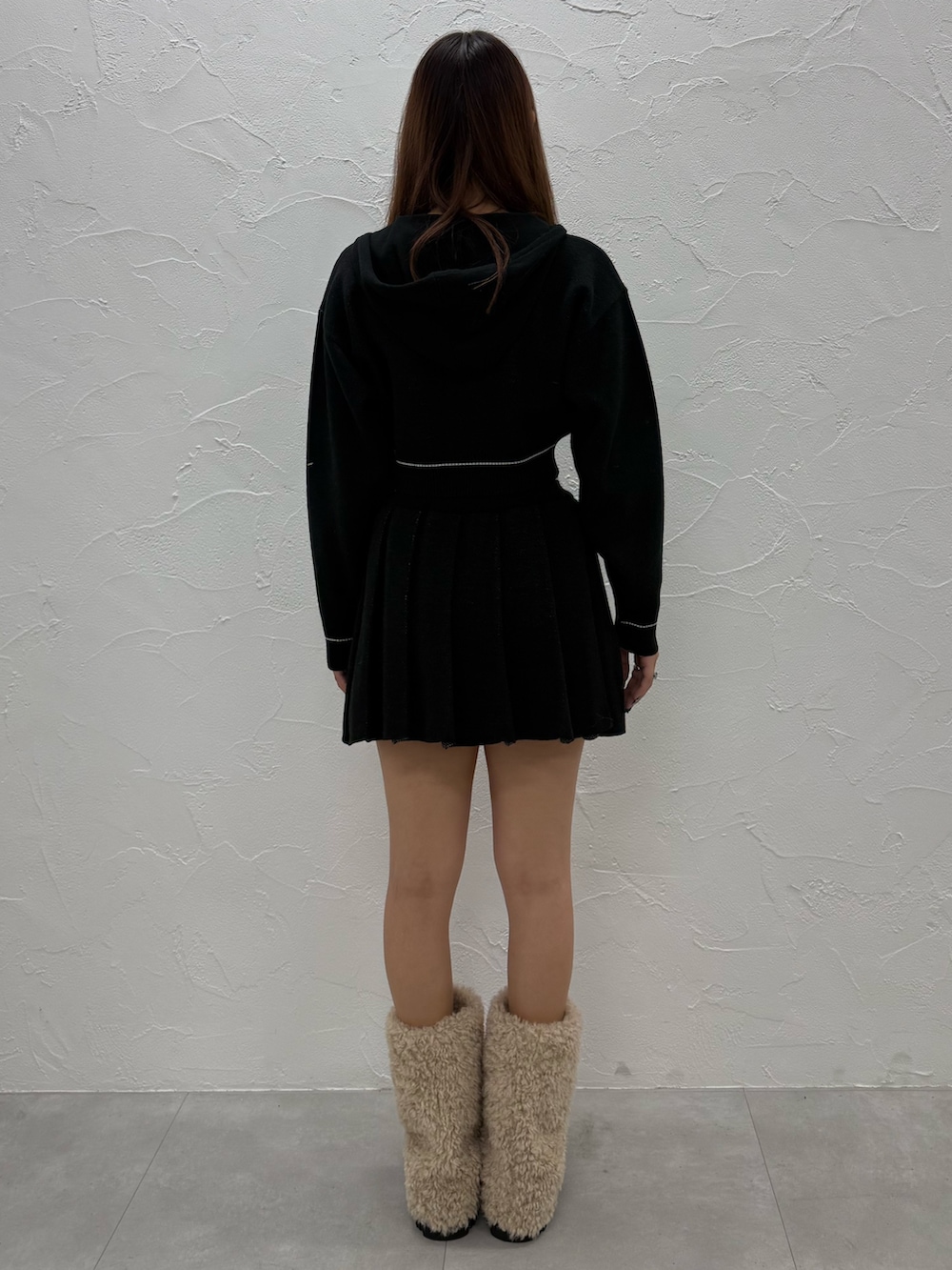 ブラック系のスカート、ホワイト系のブーツ、ブラック系のニット/セーターを着用したレディースの冬コーディネートの3枚目の写真