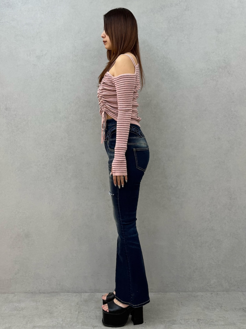 ピンク系のニット/セーター、ブルー系のデニムパンツ、ブラック系のサンダルを着用したレディースの冬コーディネートの2枚目の写真