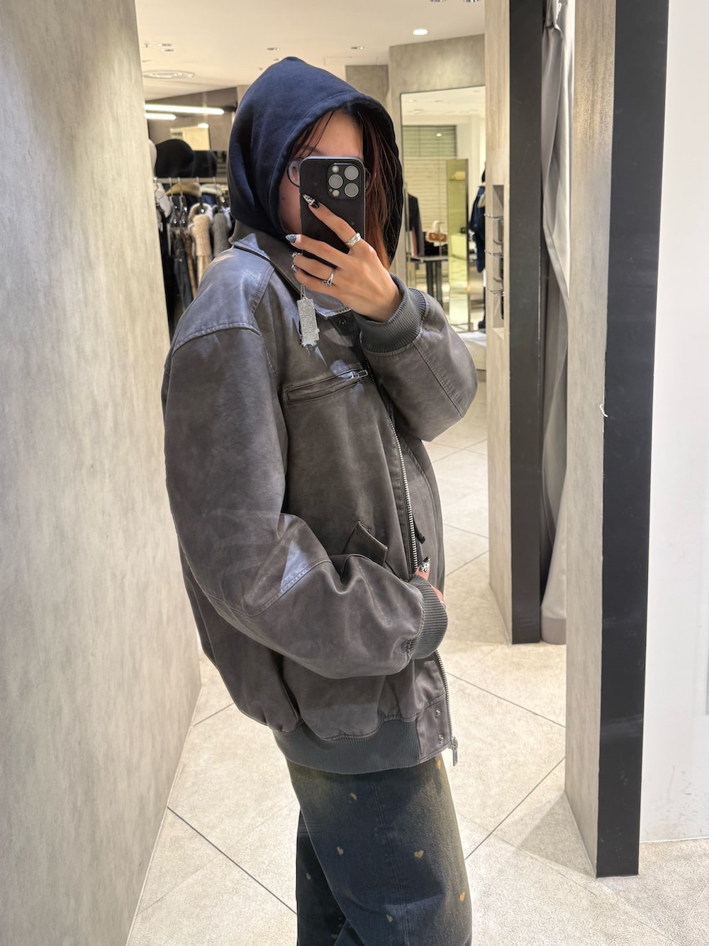 ブラック系のパーカー、グレー系のブルゾン、ブルー系のデニムパンツを着用したレディースの秋コーディネートの5枚目の写真