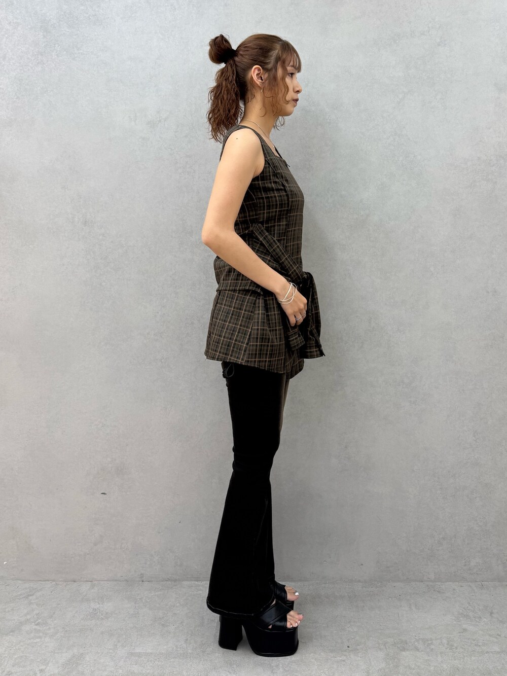 ブラウン系のワンピース、ブラック系のデニムパンツ、ブラック系のサンダルを着用したレディースの夏コーディネートの2枚目の写真