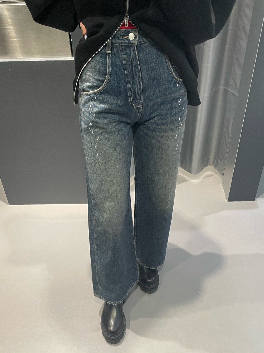 ブラック系のパーカー、ブルー系のデニムパンツ、ブラック系のブーツを着用したレディースの秋コーディネートの6枚目の写真