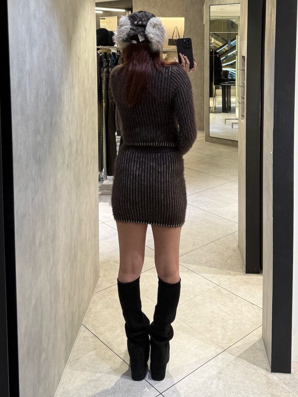 ブラウン系のニット/セーター、ブラウン系のスカート、ブラック系のブーツを着用したレディースの秋コーディネートの3枚目の写真