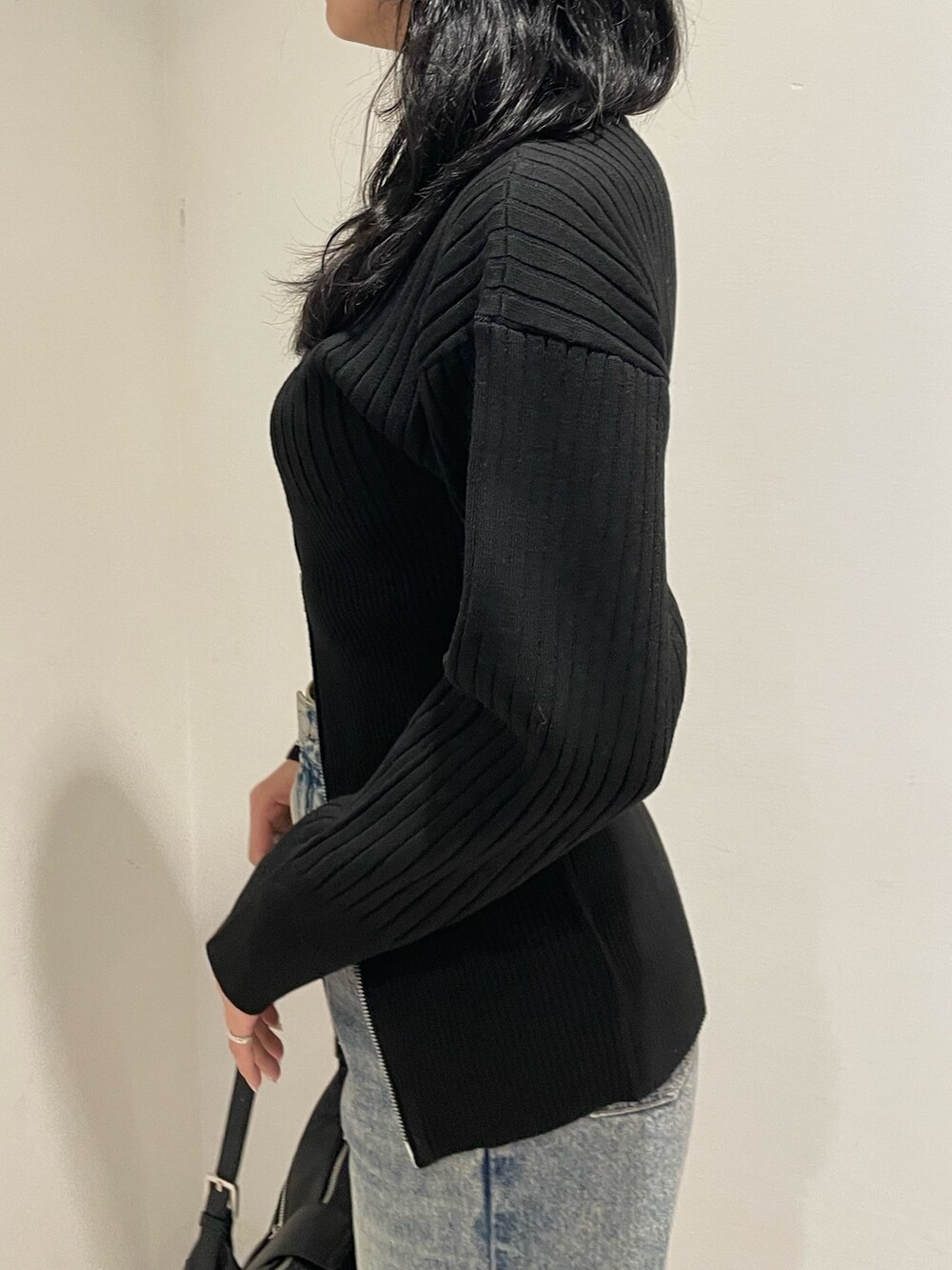 ブラック系のニット/セーター、ブルー系のデニムパンツ、ブラック系のハンドバッグを着用したレディースの冬コーディネートの5枚目の写真