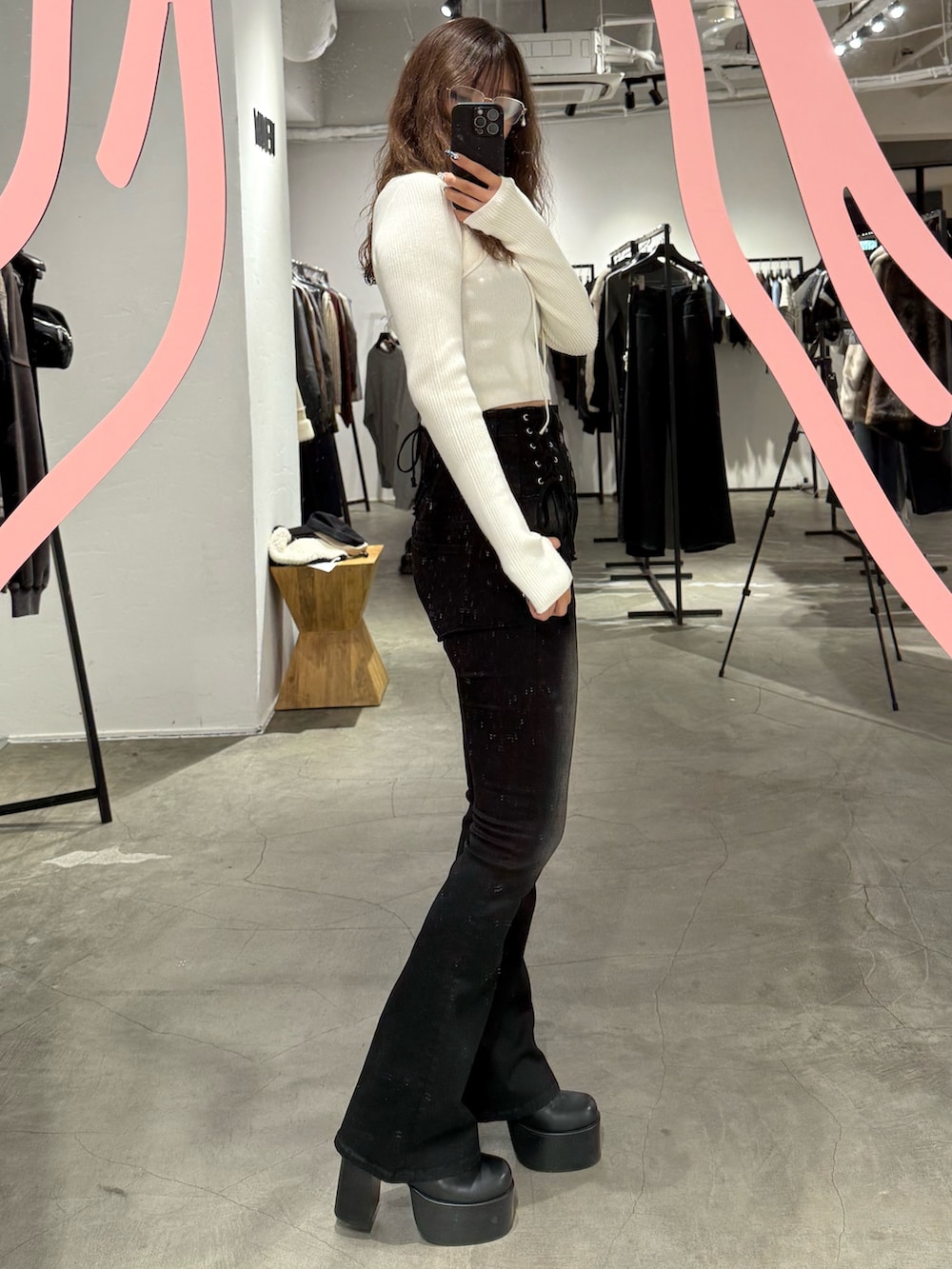 ホワイト系のニット/セーター、ブラック系のデニムパンツ、ブラック系のブーツを着用したレディースの秋コーディネートの2枚目の写真