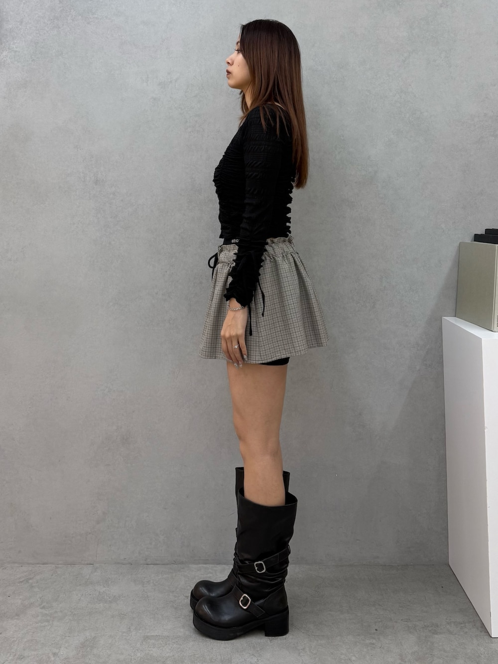 ブラック系のTシャツ/カットソー、ブラック系のスカート、ブラック系のブーツを着用したレディースの冬コーディネートの2枚目の写真