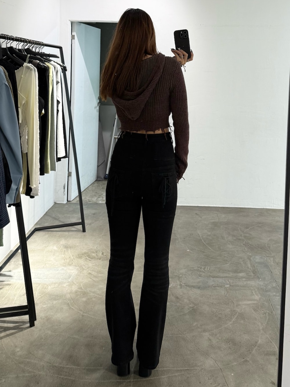 レッド系のニット/セーター、ブラック系のデニムパンツ、ブラック系のブーツを着用したレディースの冬コーディネートの3枚目の写真