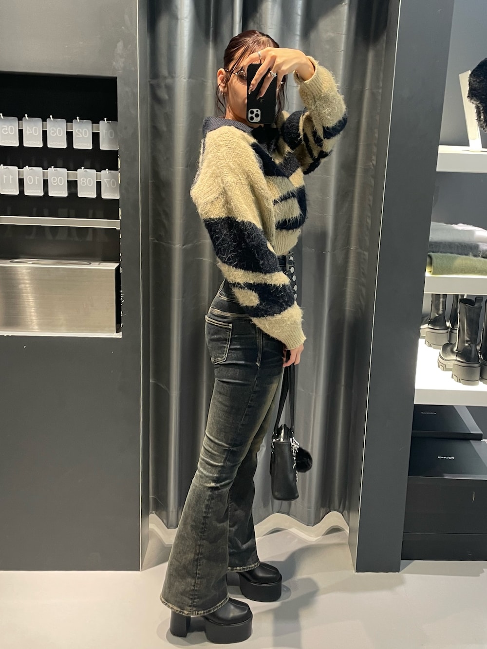 ブルー系のニット/セーター、ブルー系のデニムパンツ、ブラック系のショルダーバッグを着用したレディースの冬コーディネートの2枚目の写真