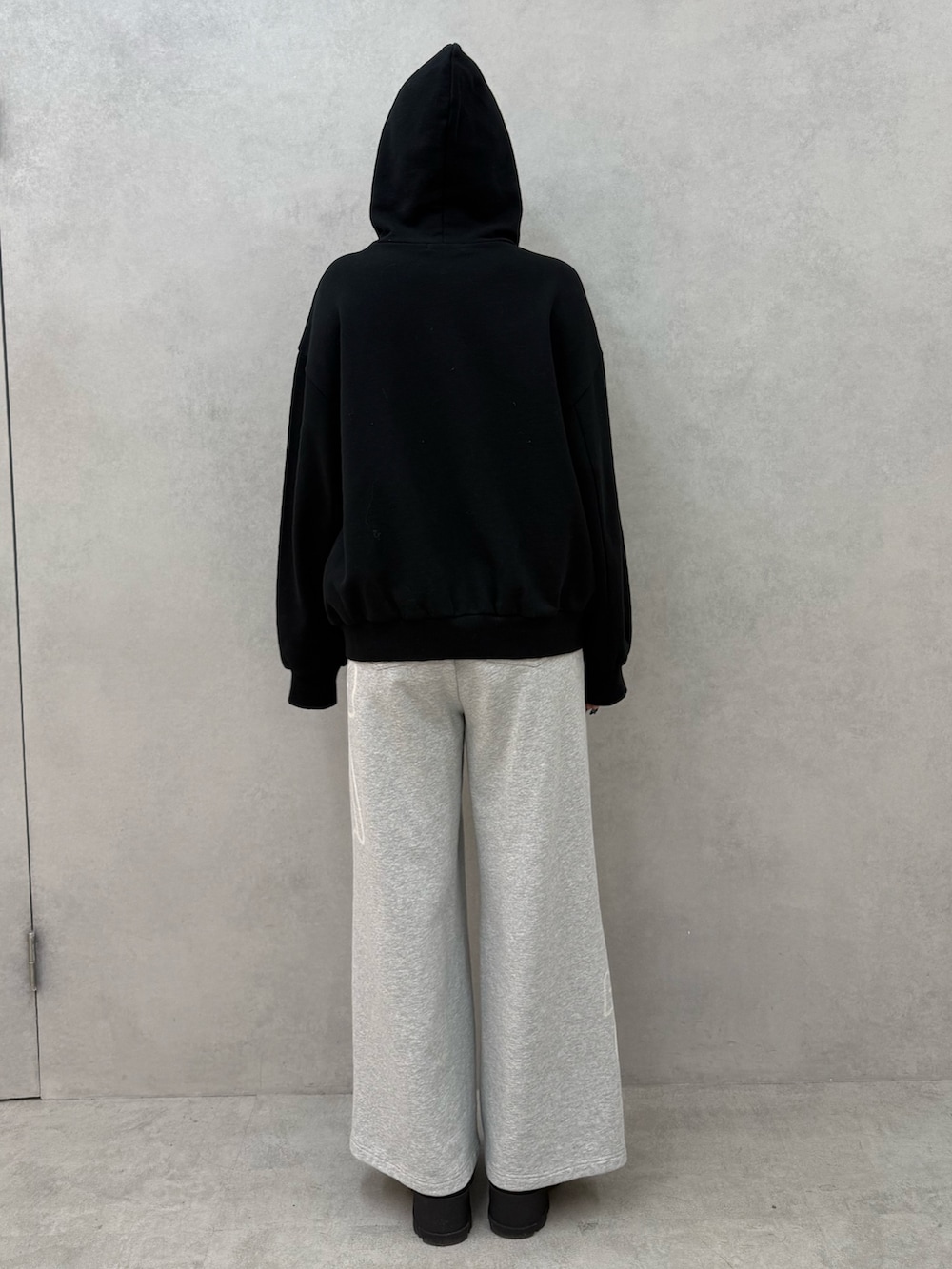 ブラック系のパーカー、グレー系のスウェットパンツ、ブラック系のブーツを着用したレディースの冬コーディネートの3枚目の写真