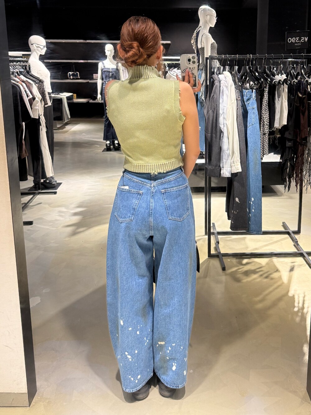 グリーン系のタンクトップ、ブルー系のデニムパンツ、ブラック系のハンドバッグを着用したレディースの夏コーディネートの3枚目の写真