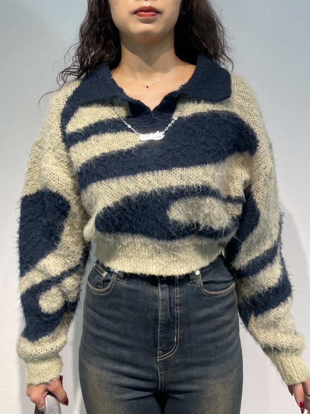 ブルー系のニット/セーター、ブルー系のデニムパンツ、シルバー系のハンドバッグを着用したレディースの秋コーディネートの4枚目の写真