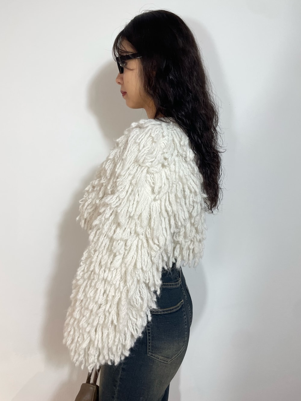 ホワイト系のニット/セーター、ブルー系のデニムパンツ、ブラウン系のショルダーバッグを着用したレディースの秋コーディネートの5枚目の写真