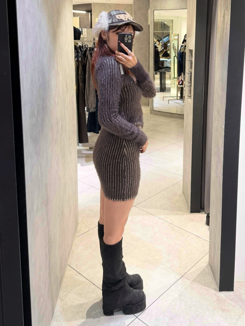 ブラウン系のニット/セーター、ブラウン系のスカート、ブラック系のブーツを着用したレディースの秋コーディネートの2枚目の写真