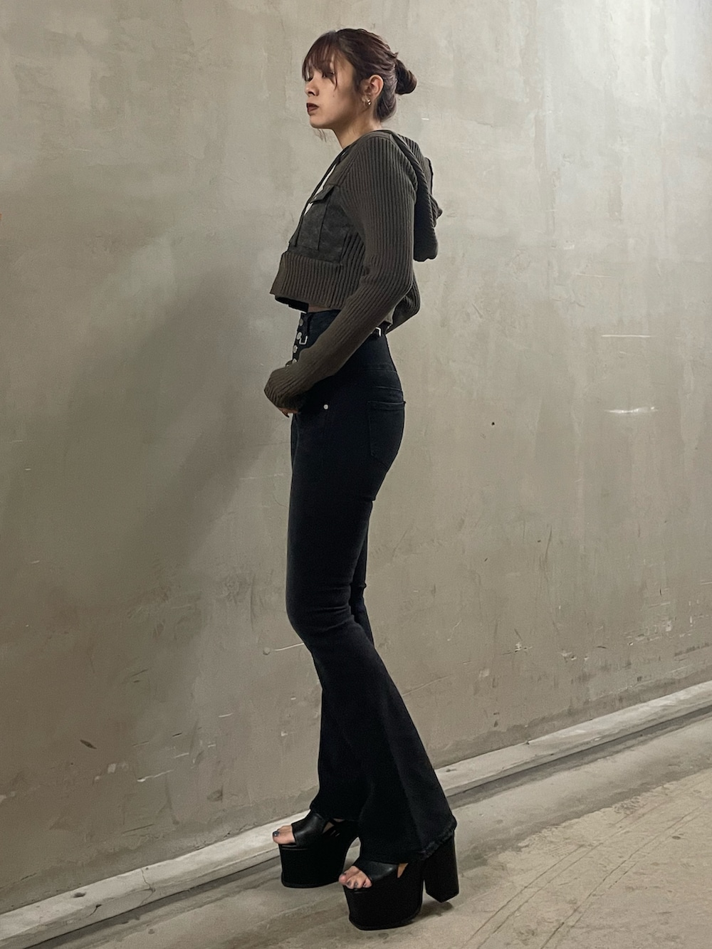 グリーン系のニット/セーター、ブラック系のデニムパンツ、ブラック系のサンダルを着用したレディースの春コーディネートの2枚目の写真