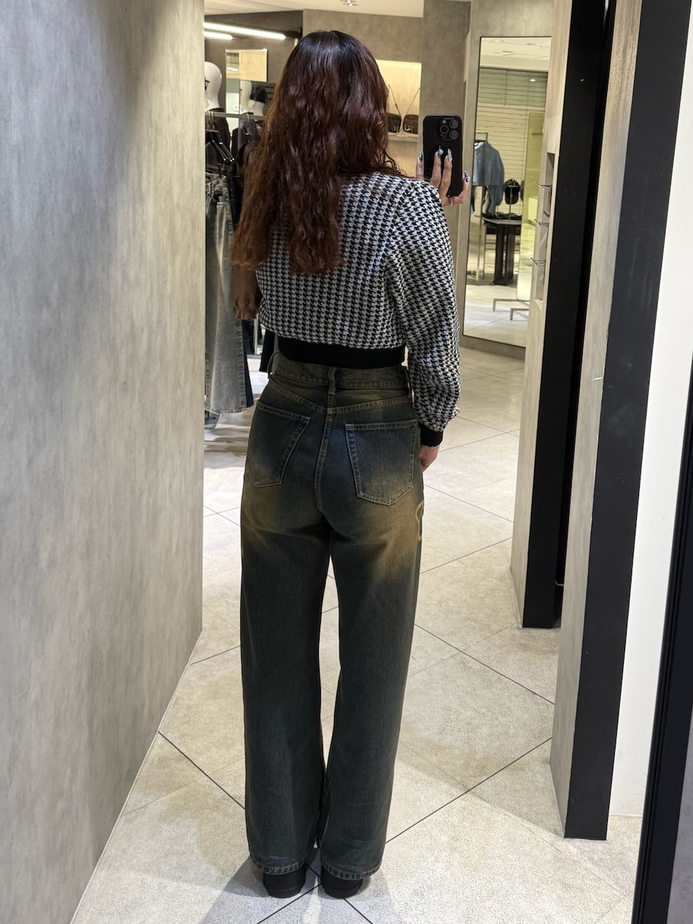 ブラック系のニット/セーター、ブルー系のデニムパンツ、ブラック系のブーツを着用したレディースの秋コーディネートの3枚目の写真