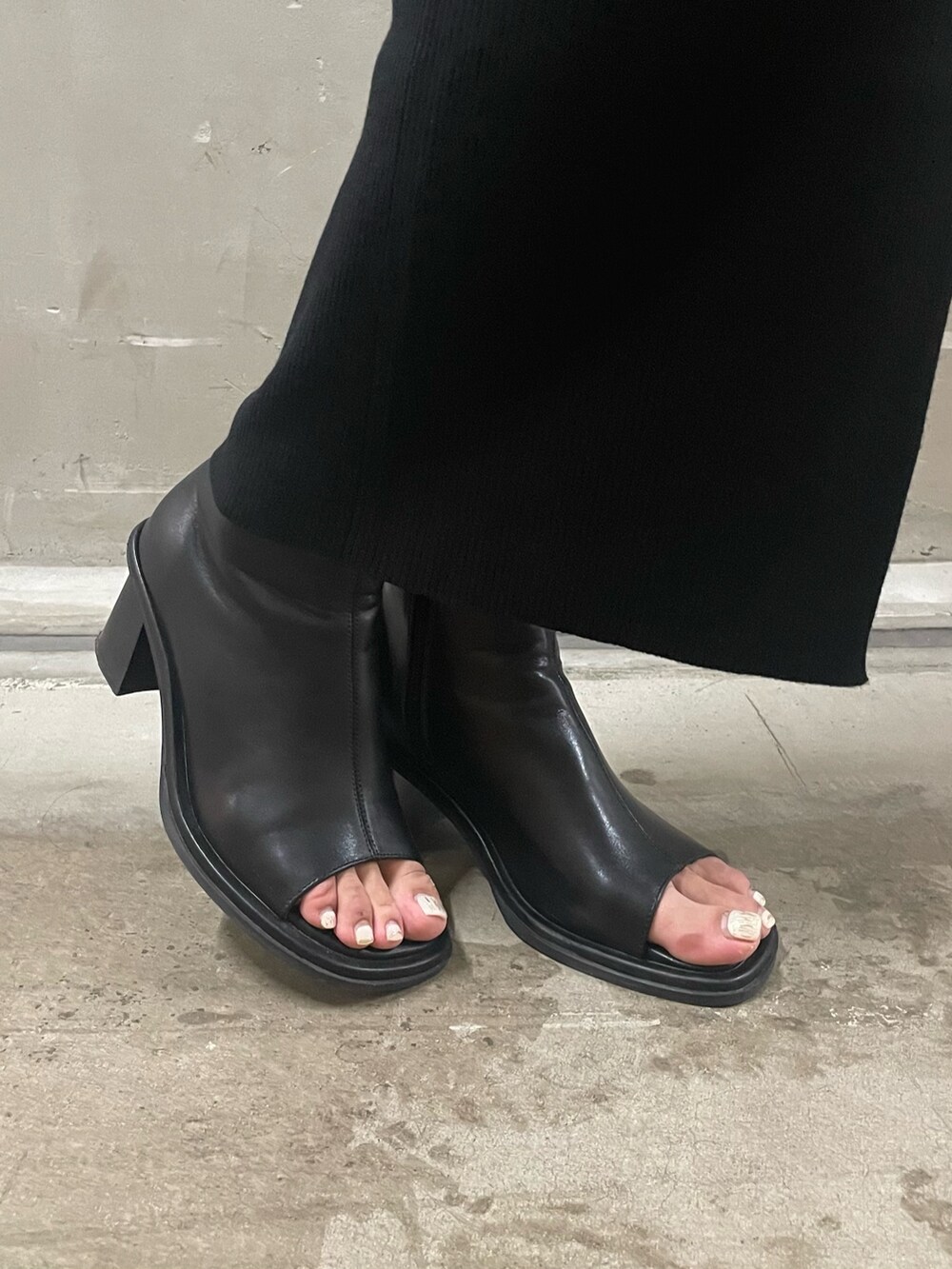 ブラック系のハンドバッグ、ブラック系のスカート、ブラック系のブーツを着用したレディースの秋コーディネートの6枚目の写真