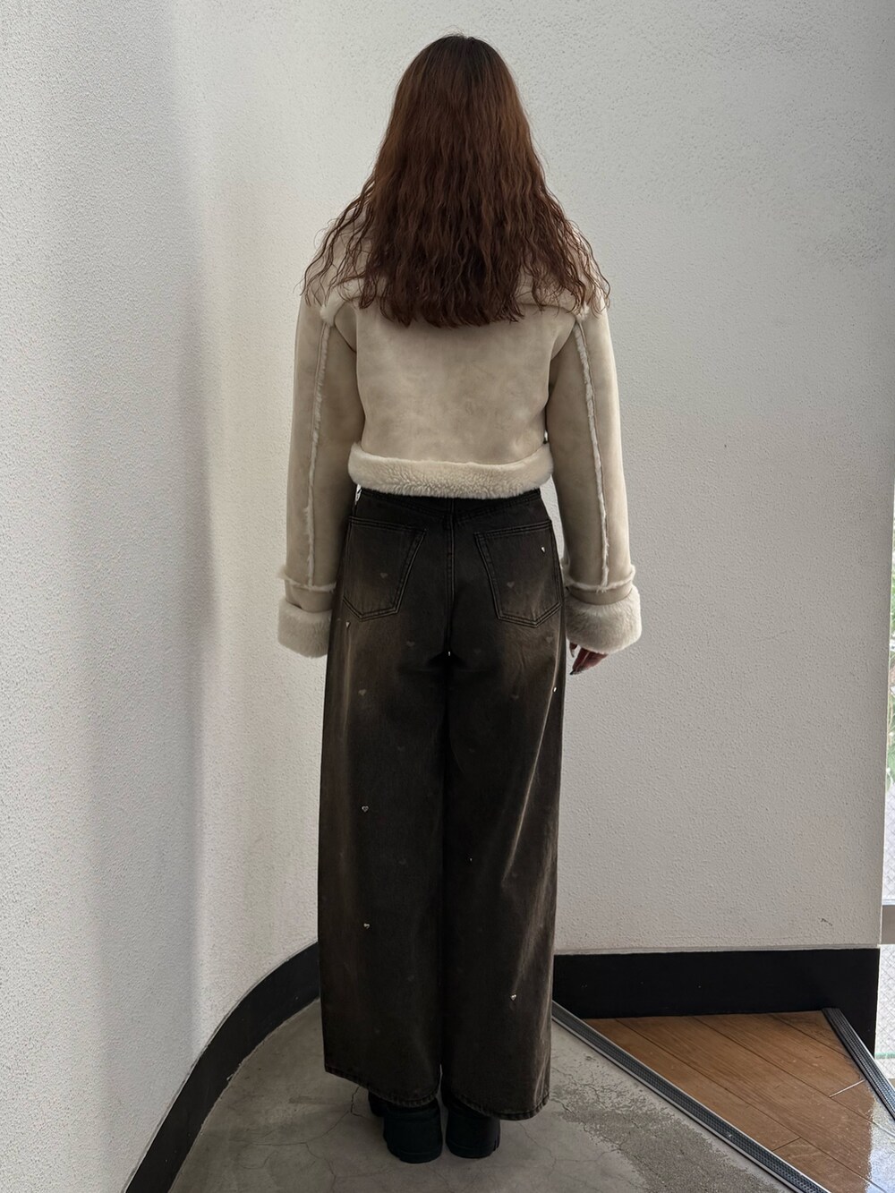 ホワイト系のブルゾン、ブラック系のTシャツ/カットソー、ブラウン系のデニムパンツを着用したレディースの秋コーディネートの3枚目の写真