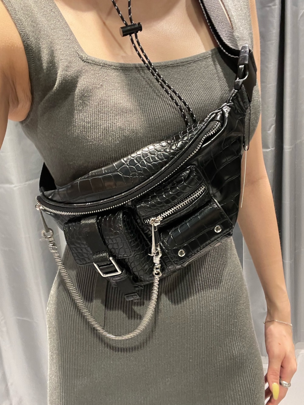 ブラック系のハンドバッグ、グレー系のワンピース、ブラック系のサンダルを着用したレディースの春コーディネートの7枚目の写真