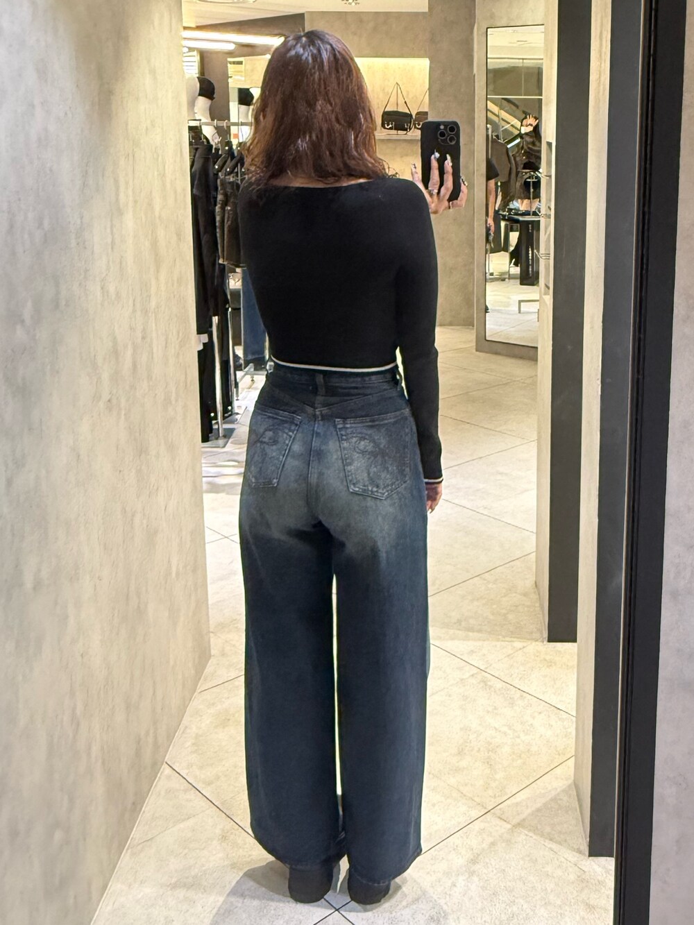 ブラック系のブーツ、ブラック系のニット/セーター、ブルー系のデニムパンツを着用したレディースの秋コーディネートの3枚目の写真