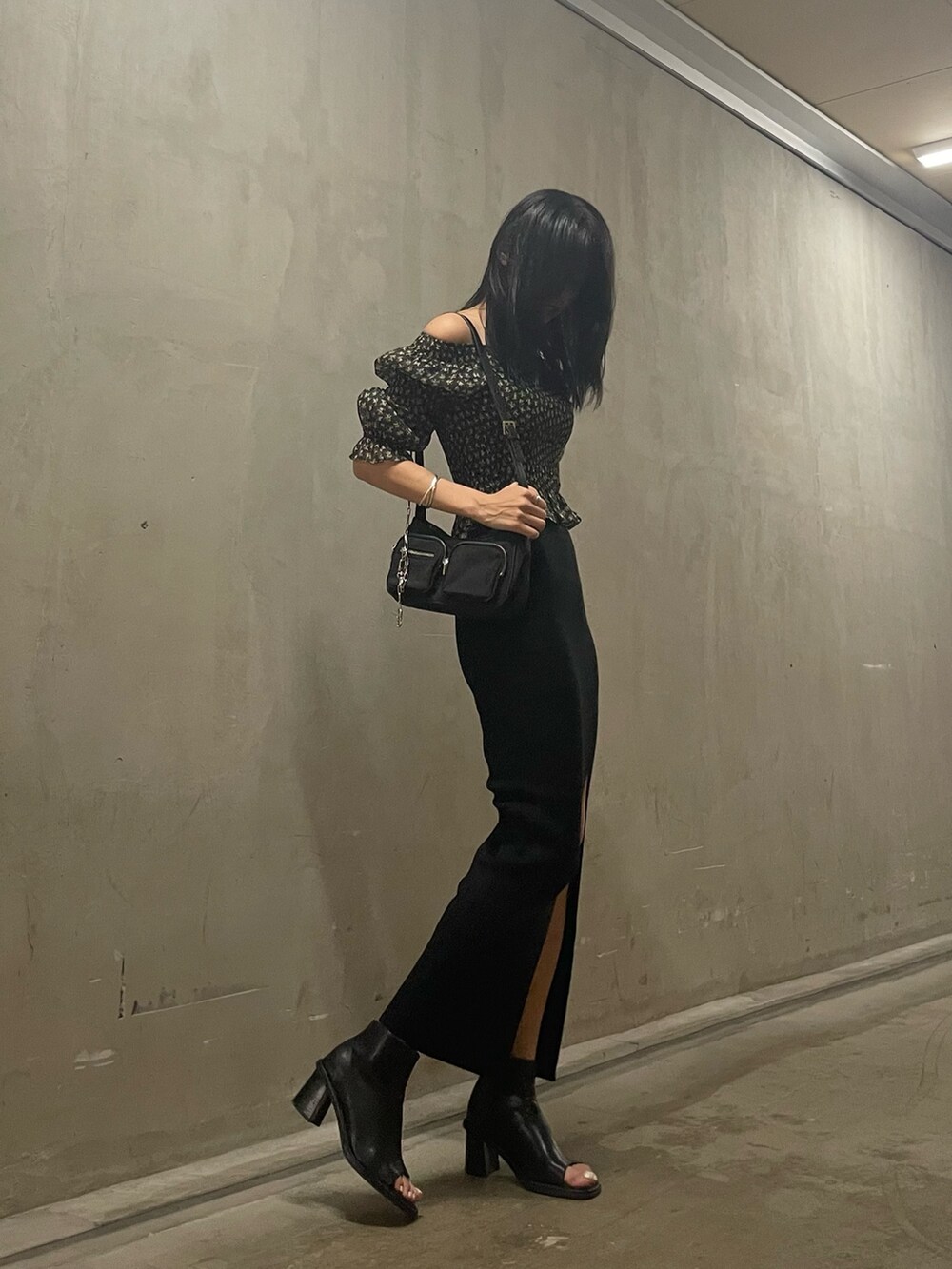 ブラック系のハンドバッグ、ブラック系のスカート、ブラック系のブーツを着用したレディースの秋コーディネートの2枚目の写真