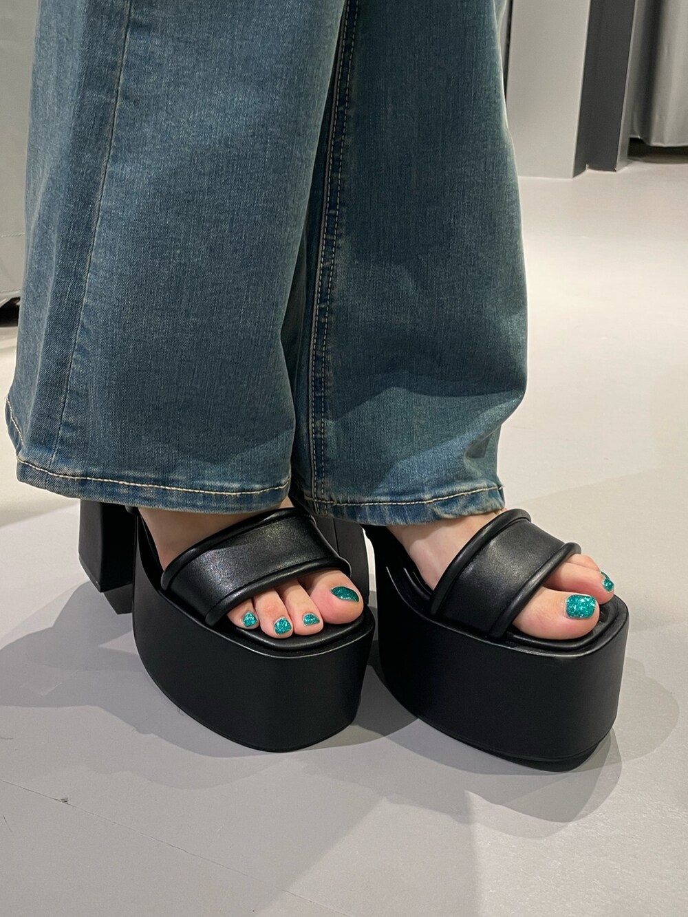 ブラック系のデニムパンツ、ブラック系のサンダル、ブルー系のTシャツ/カットソーを着用したレディースの夏コーディネートの9枚目の写真