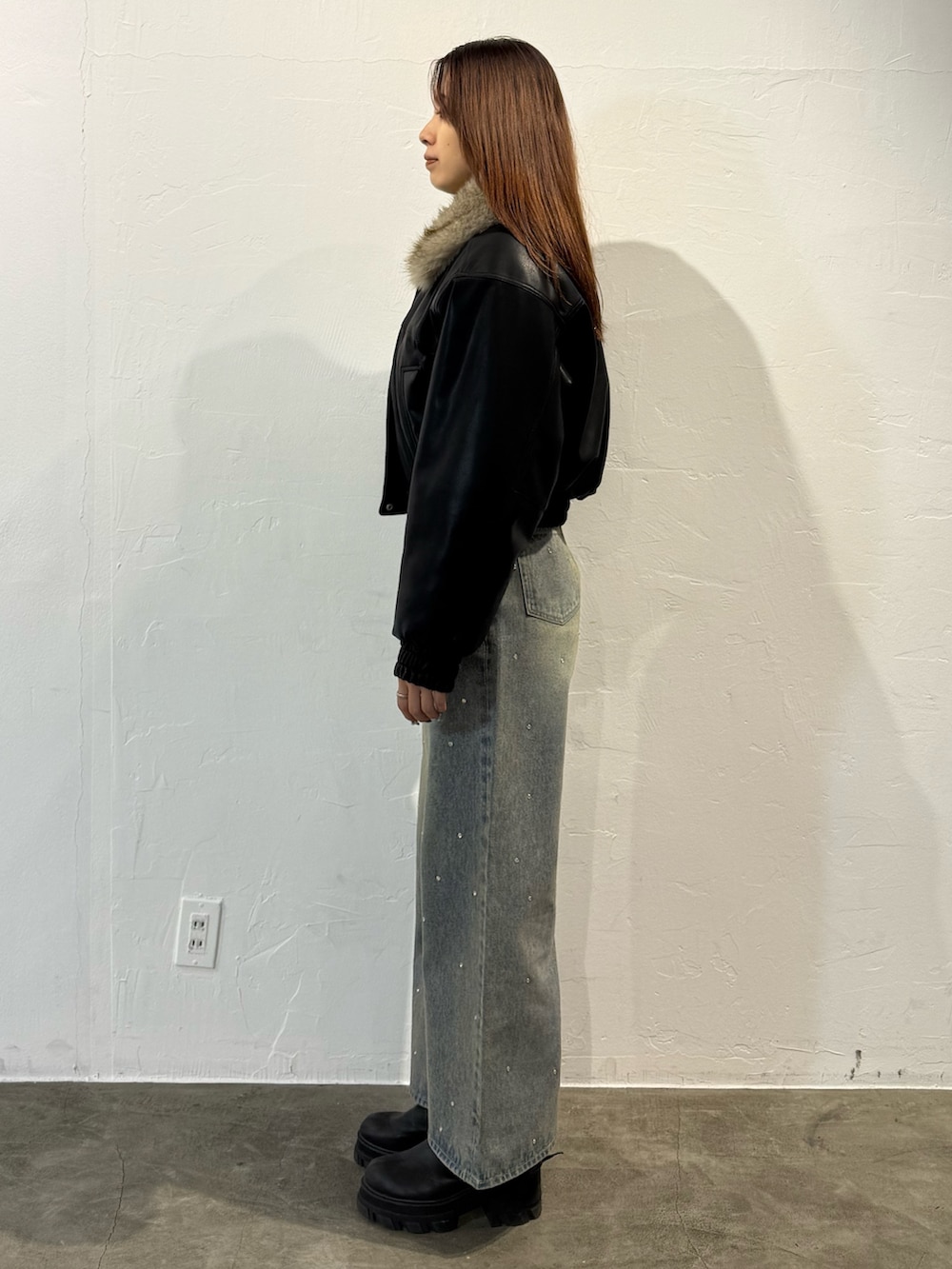 ブラック系のブルゾン、ブルー系のデニムパンツ、ブラック系のブーツを着用したレディースの冬コーディネートの2枚目の写真