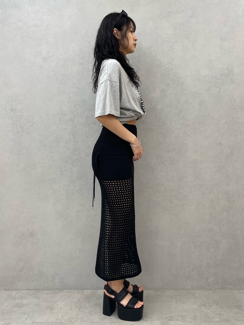 グレー系のTシャツ/カットソー、ブラック系のスカート、ブラック系のサンダルを着用したレディースの春コーディネートの2枚目の写真