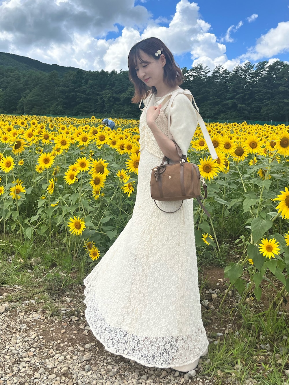 ホワイト系のワンピース、イエロー系のボストンバッグ、ホワイト系のサンダルを着用したレディースの夏コーディネートの2枚目の写真