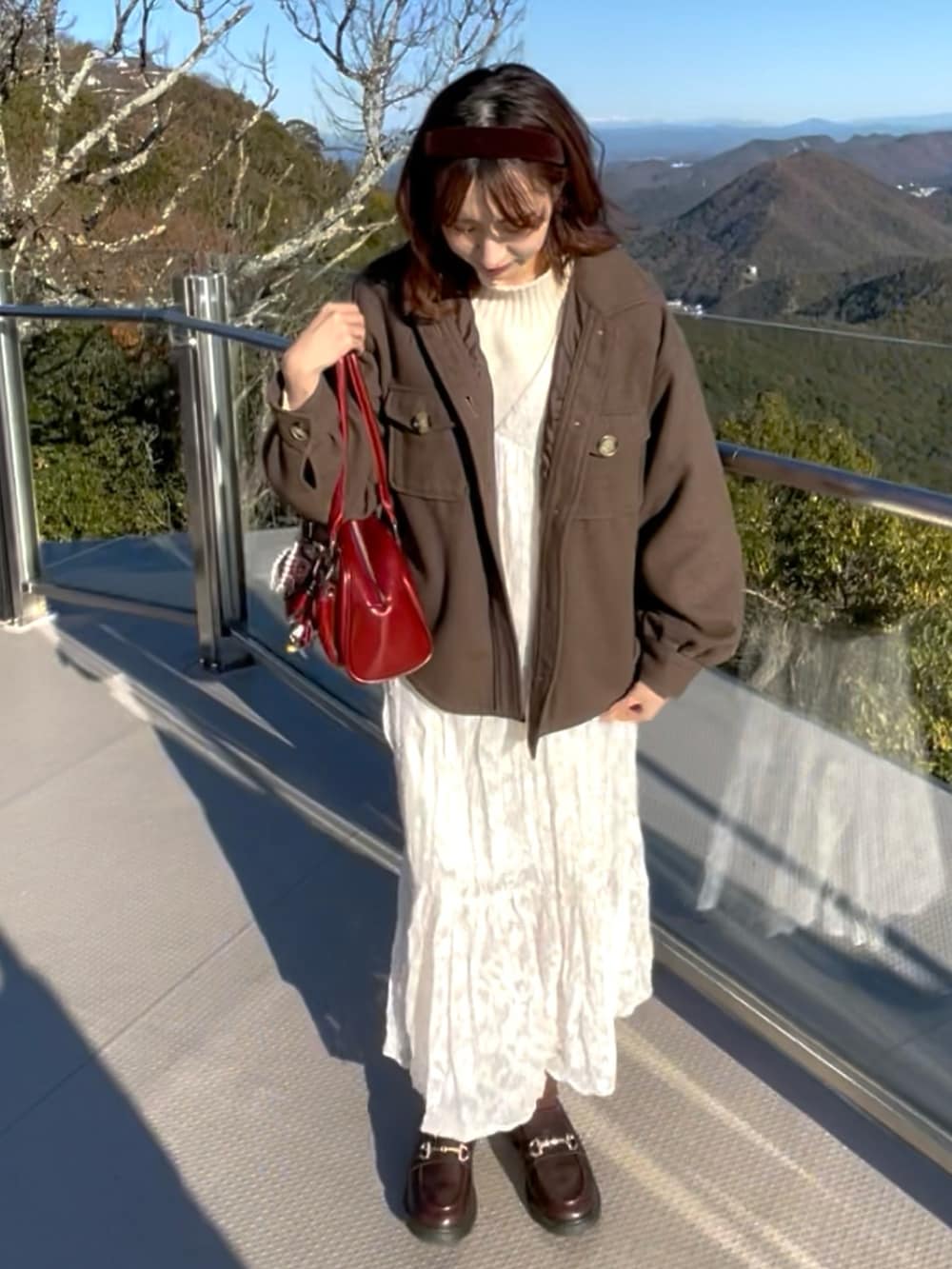 ホワイト系のワンピース、レッド系のショルダーバッグ、ブラウン系のローファーを着用したレディースの冬コーディネートの2枚目の写真