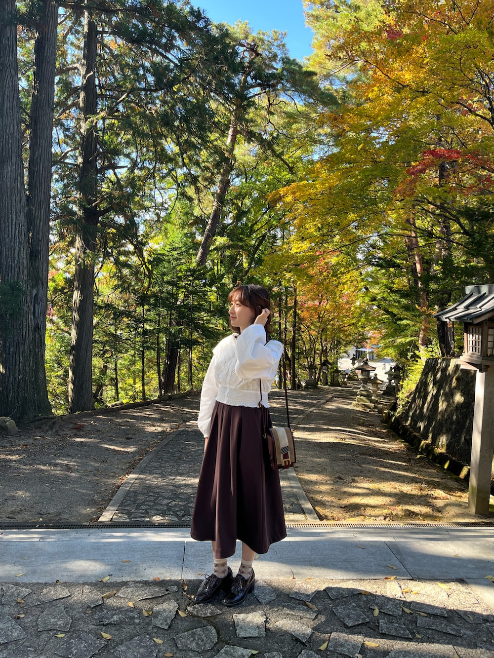 ブラウン系のワンピース、ホワイト系のシャツ/ブラウス、ブラウン系のパンプスを着用したレディースの秋コーディネートの2枚目の写真