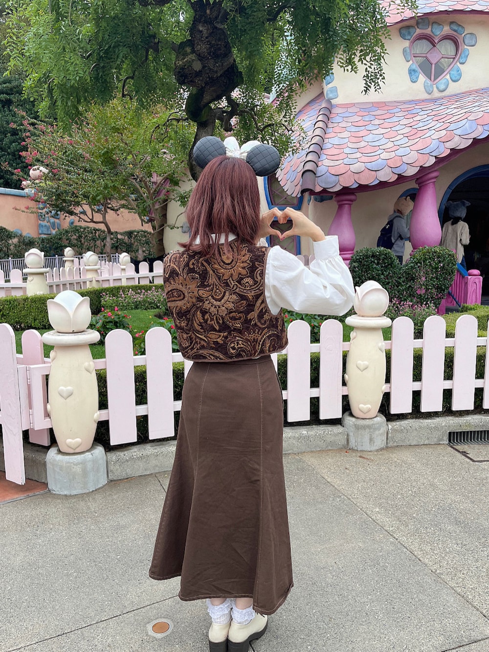 ブラウン系のベスト、ホワイト系のブーツ、ブラウン系のデニムスカートを着用したレディースの春コーディネートの2枚目の写真