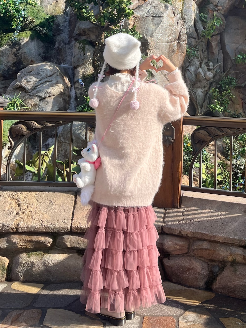 ピンク系のスカート、ピンク系のカーディガン/ボレロ、ベージュ系のブーツを着用したレディースの春コーディネートの2枚目の写真