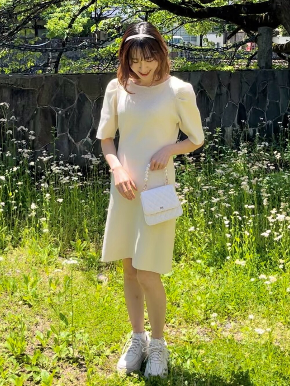 ホワイト系のワンピース、ホワイト系のスニーカー、ホワイト系のハンドバッグを着用したレディースの夏コーディネートの2枚目の写真