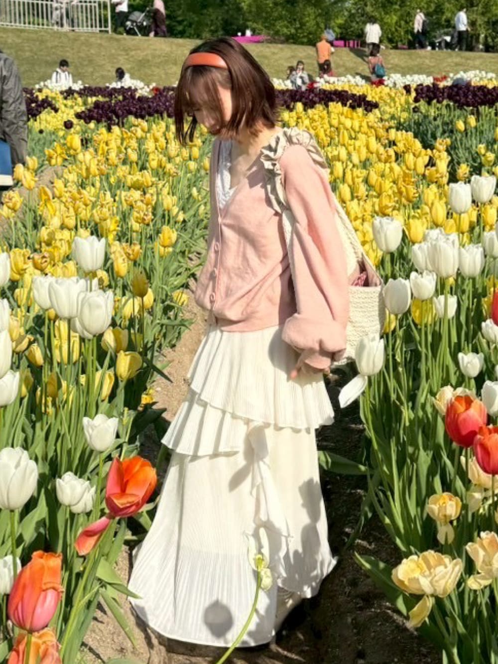 ホワイト系のスカート、ピンク系のカーディガン/ボレロ、ホワイト系のハンドバッグを着用したレディースの春コーディネートの2枚目の写真