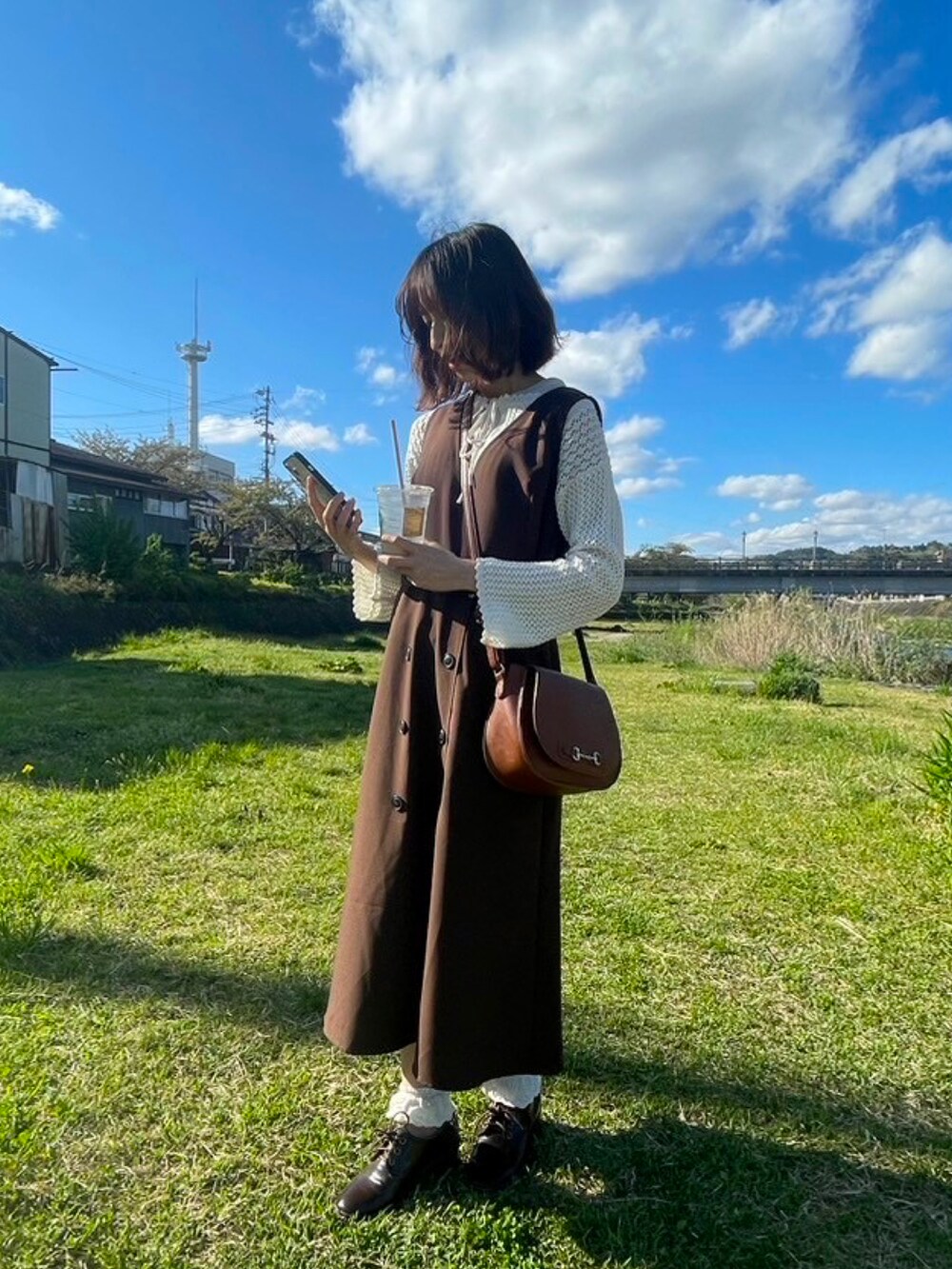 ブラウン系のワンピース、ホワイト系のシャツ/ブラウスを着用したレディースの春コーディネートの2枚目の写真