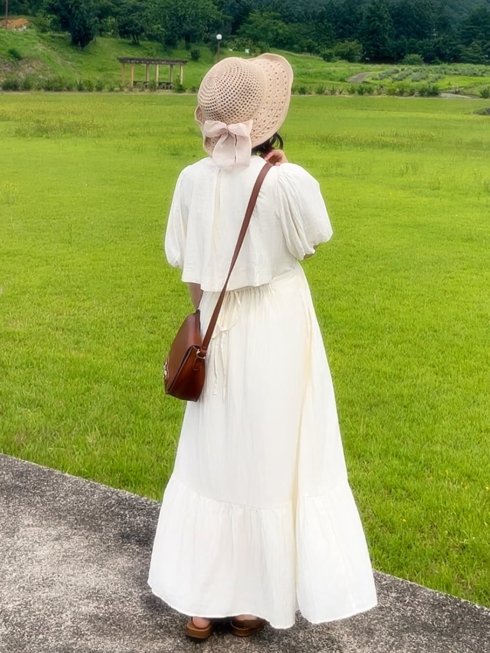 ホワイト系のワンピース、ベージュ系のハットを着用したレディースの夏コーディネートの2枚目の写真