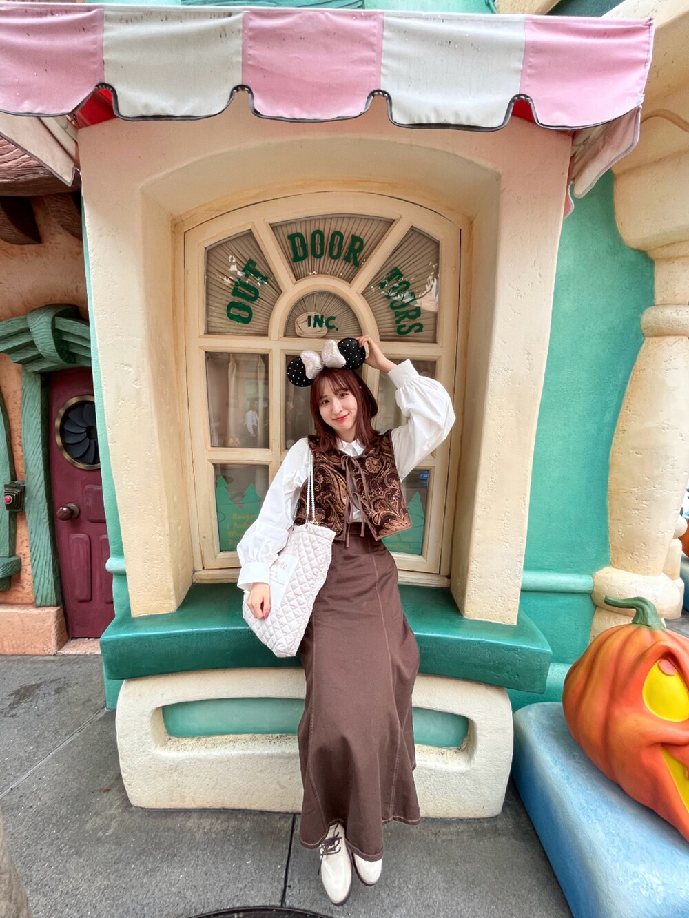 ブラウン系のベスト、ホワイト系のブーツ、ブラウン系のデニムスカートを着用したレディースの春コーディネートの3枚目の写真