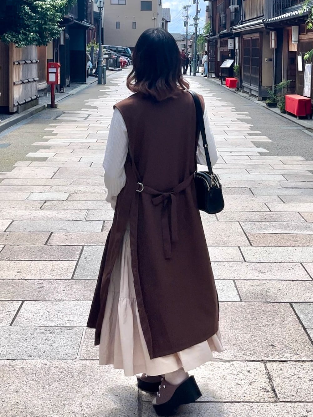 ベージュ系のワンピース、ホワイト系のシャツ/ブラウス、ピンク系のサンダルを着用したレディースの夏コーディネートの3枚目の写真