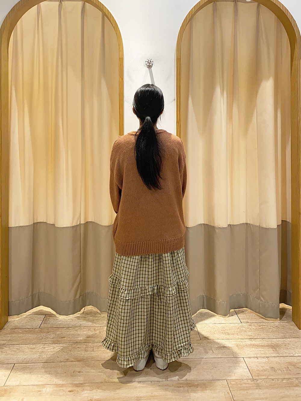 レッド系のカーディガン/ボレロ、グリーン系のスカート、ブラウン系のハンドバッグを着用したレディースの秋コーディネートの2枚目の写真