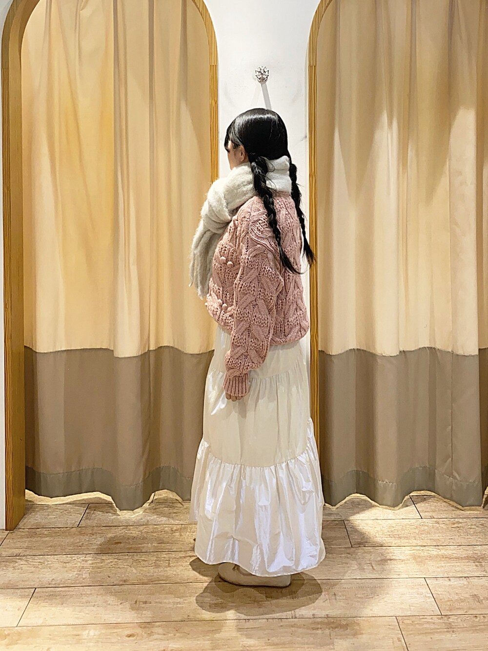 ピンク系のニット/セーター、ホワイト系のスカート、ホワイト系のストール/ショールを着用したレディースの冬コーディネートの2枚目の写真