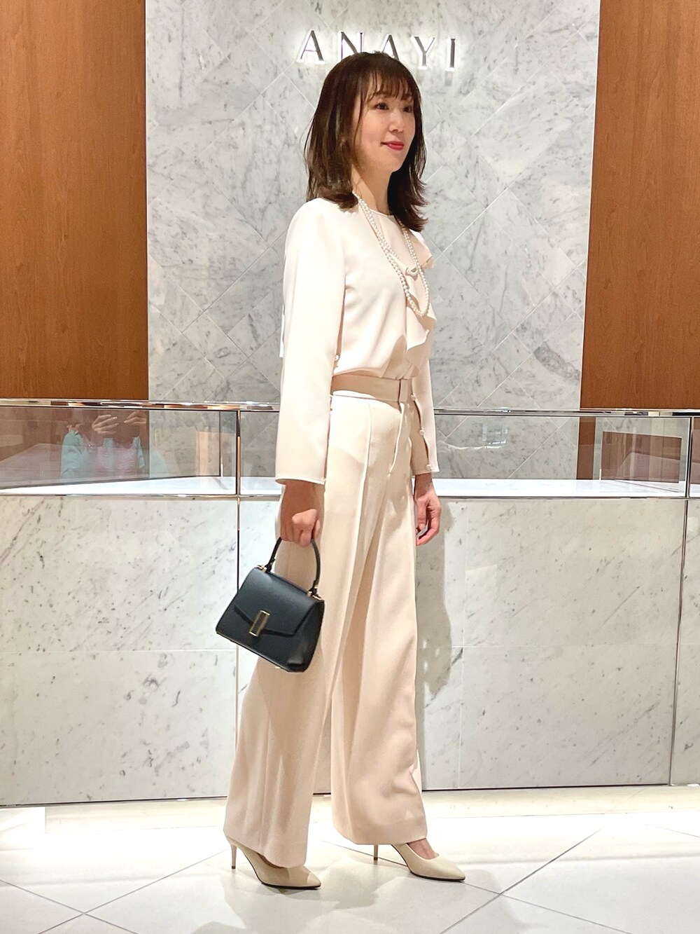 ベージュ系のシャツ/ブラウス、ベージュ系のその他パンツ、ブルー系のトートバッグを着用したレディースの冬コーディネートの4枚目の写真