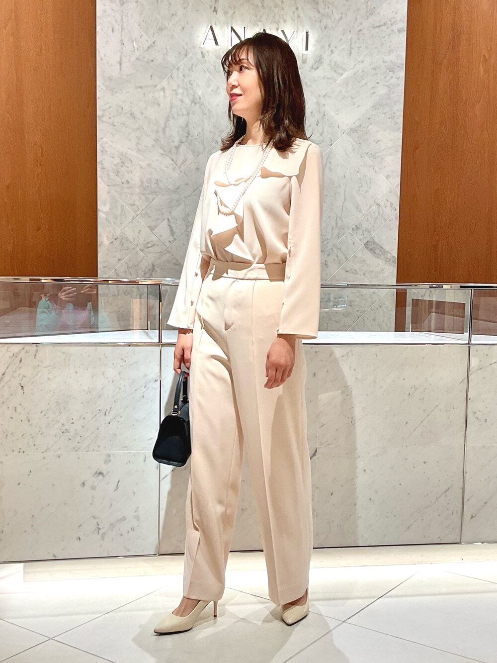 ベージュ系のシャツ/ブラウス、ベージュ系のその他パンツ、ブルー系のトートバッグを着用したレディースの冬コーディネートの3枚目の写真